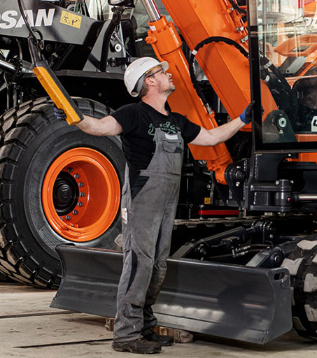 Ein Arbeiter prüft aufmerksam einen Bagger in einer Halle